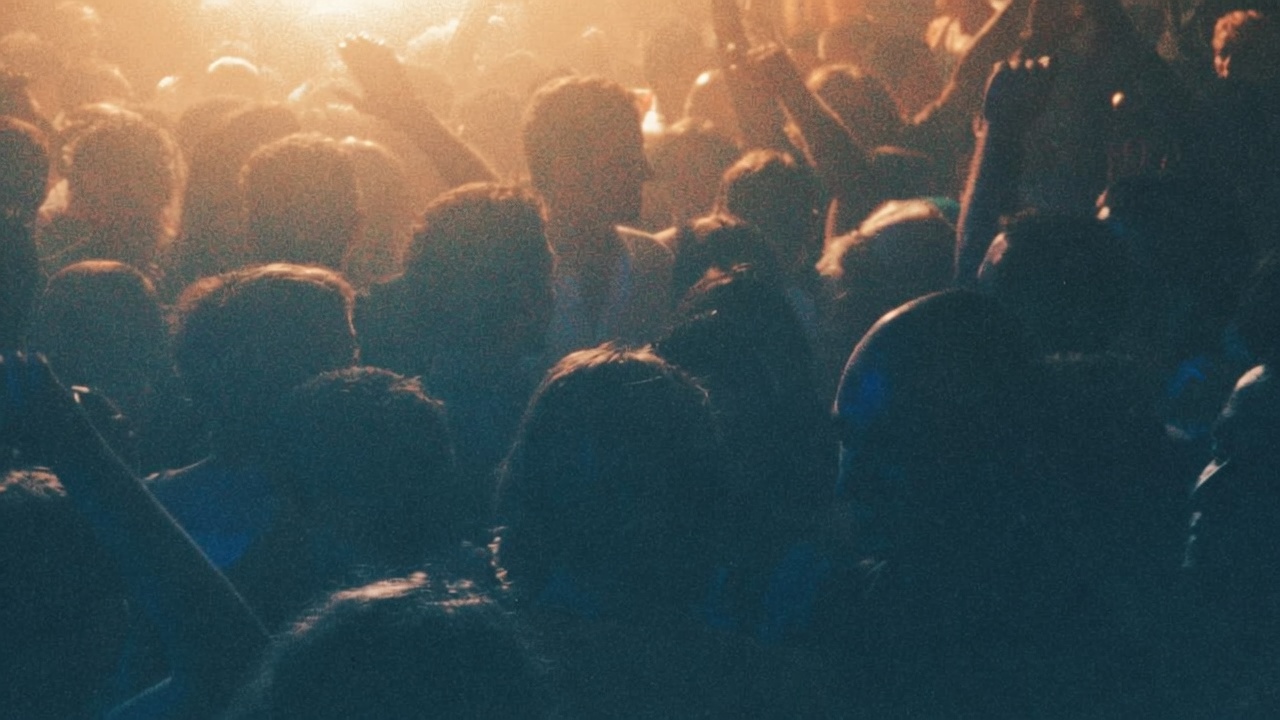 A crowded dance floor at night, hands in the air.